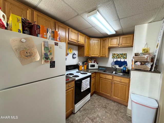 kitchen featuring white appliances, a drop ceiling, brown cabinets, and a sink