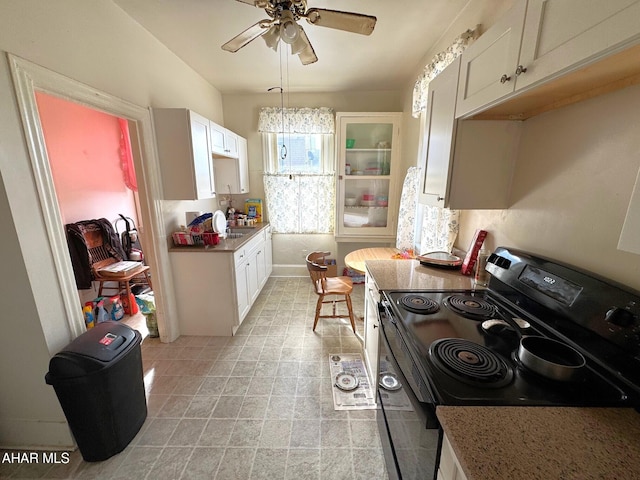 kitchen with glass insert cabinets, ceiling fan, white cabinetry, and electric stove