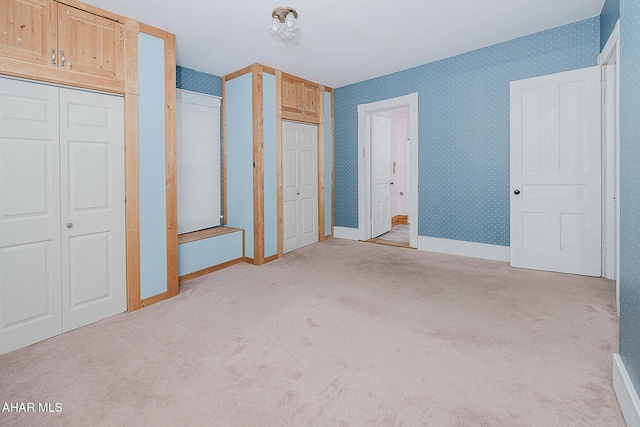 unfurnished bedroom featuring two closets and light carpet