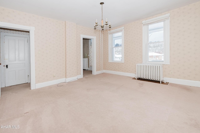 spare room featuring an inviting chandelier, radiator heating unit, and carpet floors