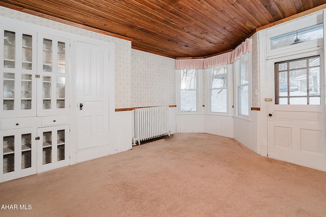 entryway with radiator heating unit, carpet flooring, and wooden ceiling