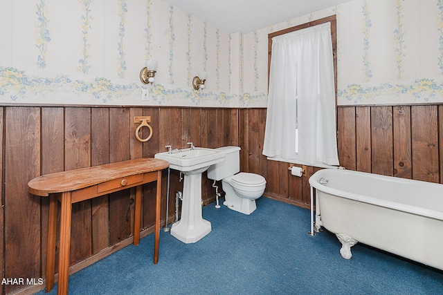 bathroom with toilet, a bathing tub, and wood walls