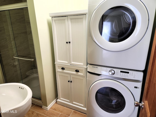 clothes washing area with sink, stacked washing maching and dryer, and light wood-type flooring