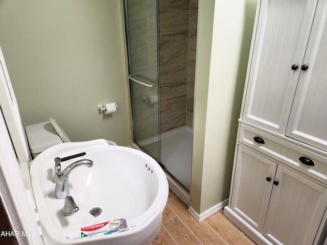 bathroom featuring sink, a shower with shower door, and hardwood / wood-style flooring