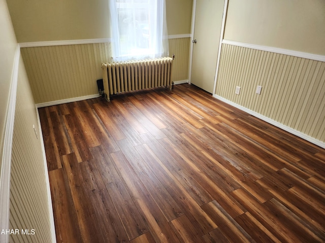 empty room featuring dark hardwood / wood-style flooring and radiator