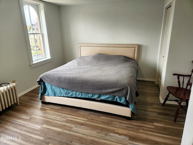 bedroom featuring wood-type flooring and radiator heating unit