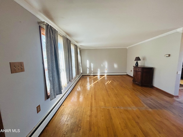 spare room featuring hardwood / wood-style flooring, baseboard heating, plenty of natural light, and crown molding