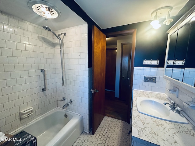 bathroom featuring tile patterned flooring, tiled shower / bath, vanity, and tile walls