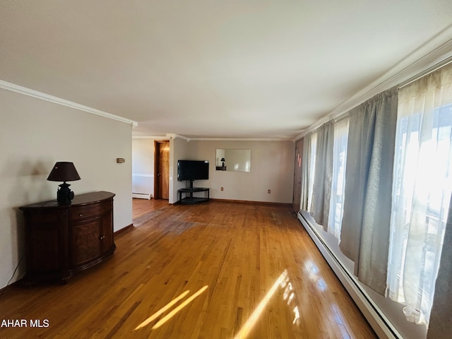 unfurnished living room featuring a wealth of natural light, hardwood / wood-style floors, ornamental molding, and a baseboard heating unit