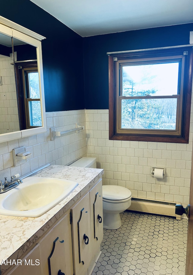 bathroom featuring tile patterned floors, tile walls, a wealth of natural light, and a baseboard heating unit