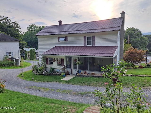 view of front of house with a yard and a sunroom