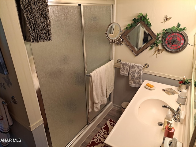 bathroom featuring wood-type flooring, a shower with door, and sink