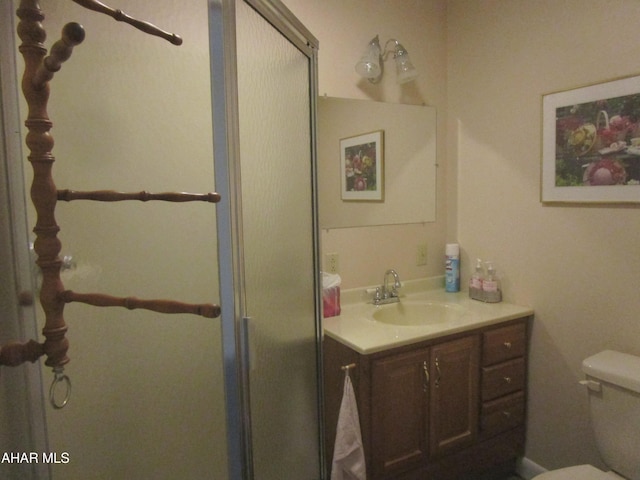 bathroom with vanity, toilet, and a shower with door