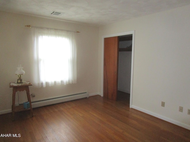 empty room featuring dark hardwood / wood-style flooring and a baseboard radiator