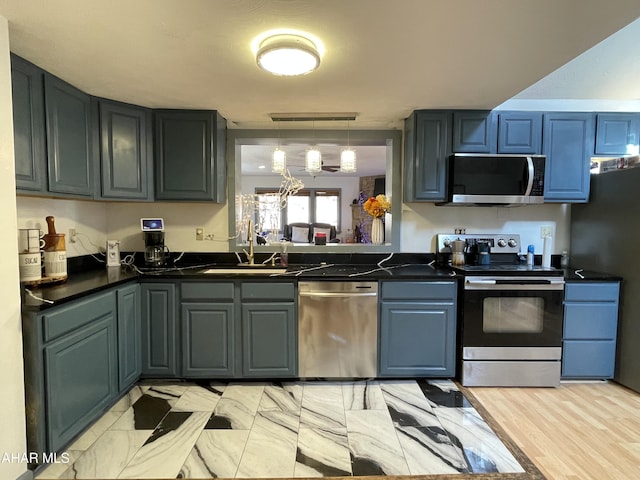 kitchen featuring stainless steel appliances, sink, light hardwood / wood-style flooring, a chandelier, and hanging light fixtures