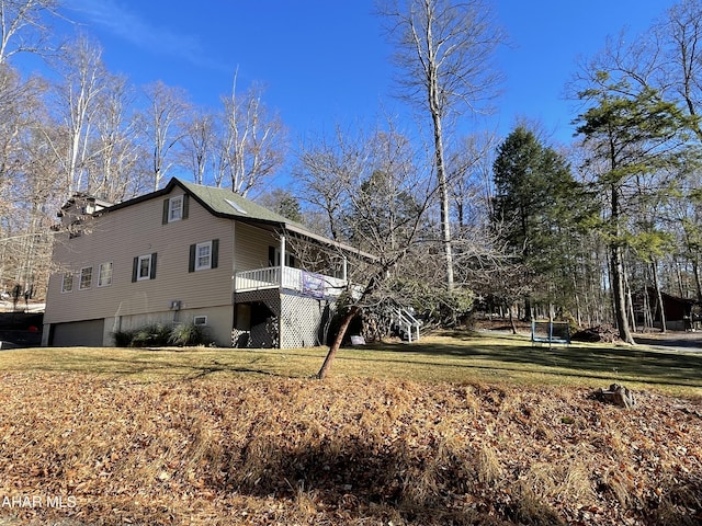 view of side of property featuring a lawn, a wooden deck, and a garage