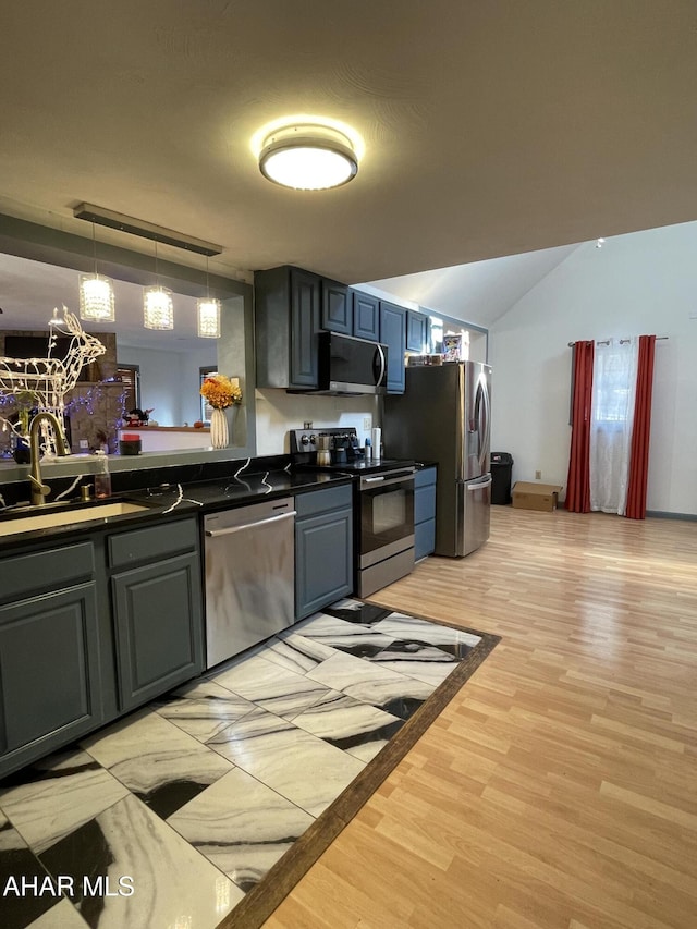 kitchen featuring decorative light fixtures, light wood-type flooring, stainless steel appliances, and sink