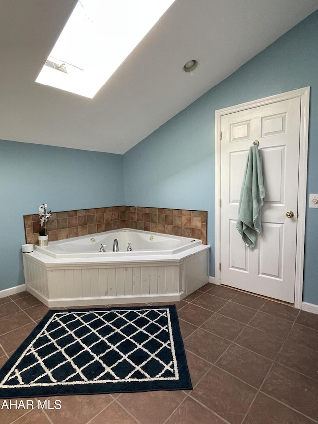 bathroom with tile patterned floors, lofted ceiling with skylight, and a relaxing tiled tub