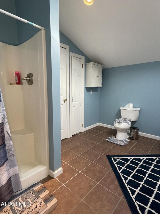 bathroom featuring tile patterned floors, toilet, vaulted ceiling, and walk in shower