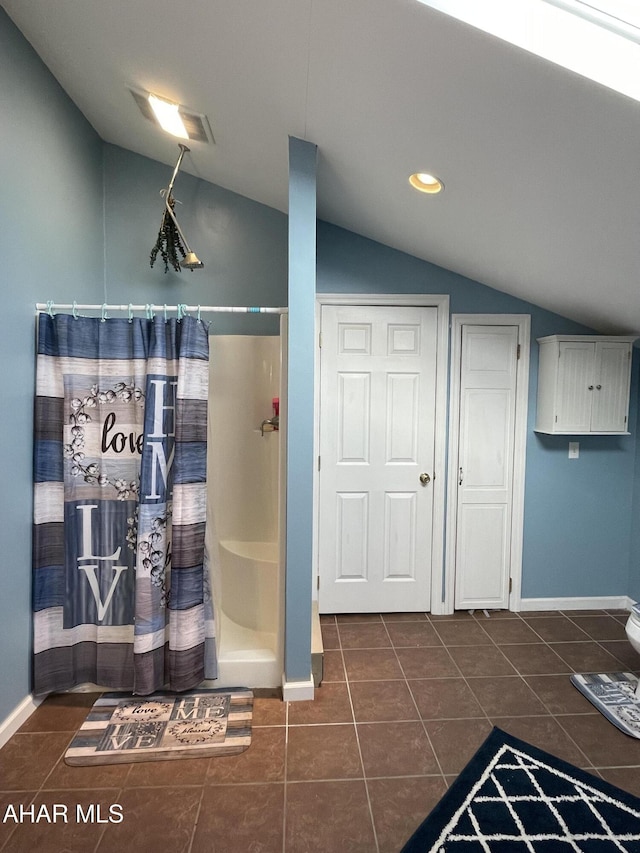 bathroom with a shower with shower curtain, tile patterned floors, and lofted ceiling