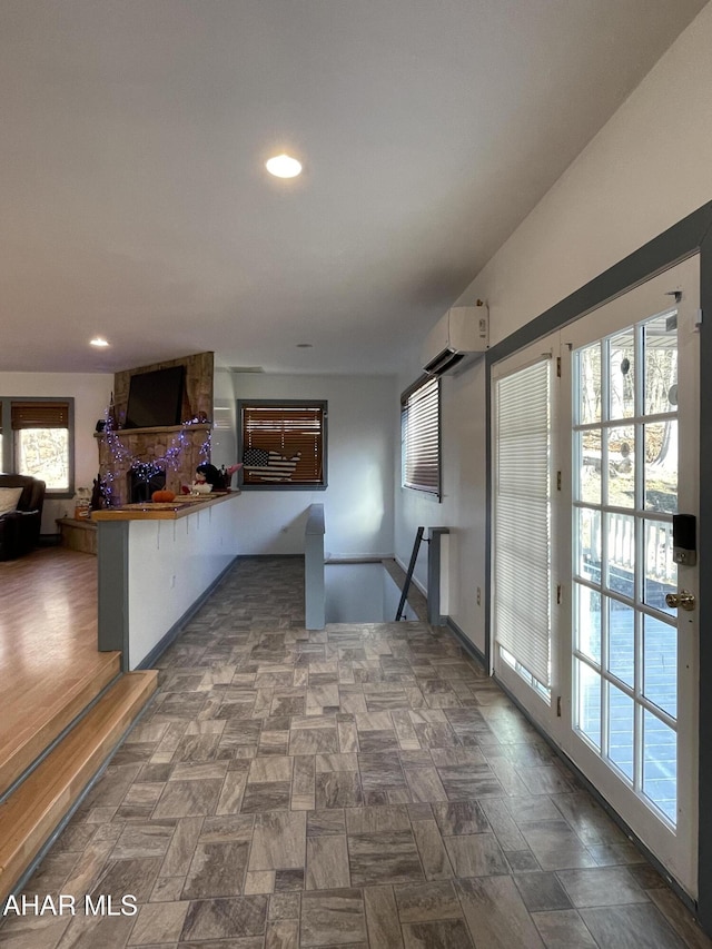 kitchen with a wall mounted air conditioner, a kitchen breakfast bar, a stone fireplace, and kitchen peninsula