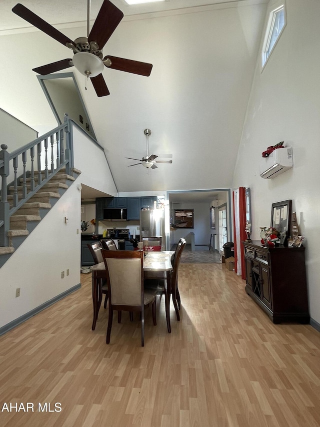 dining area with an AC wall unit, high vaulted ceiling, and light hardwood / wood-style floors