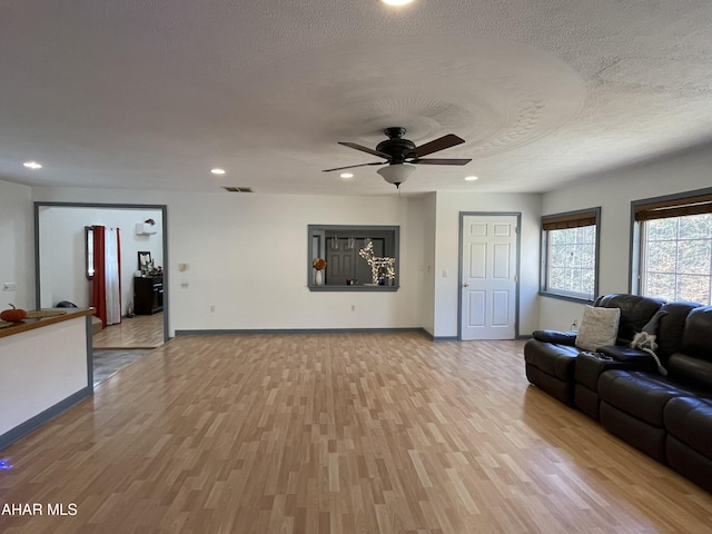 unfurnished living room with ceiling fan, a textured ceiling, and light hardwood / wood-style flooring