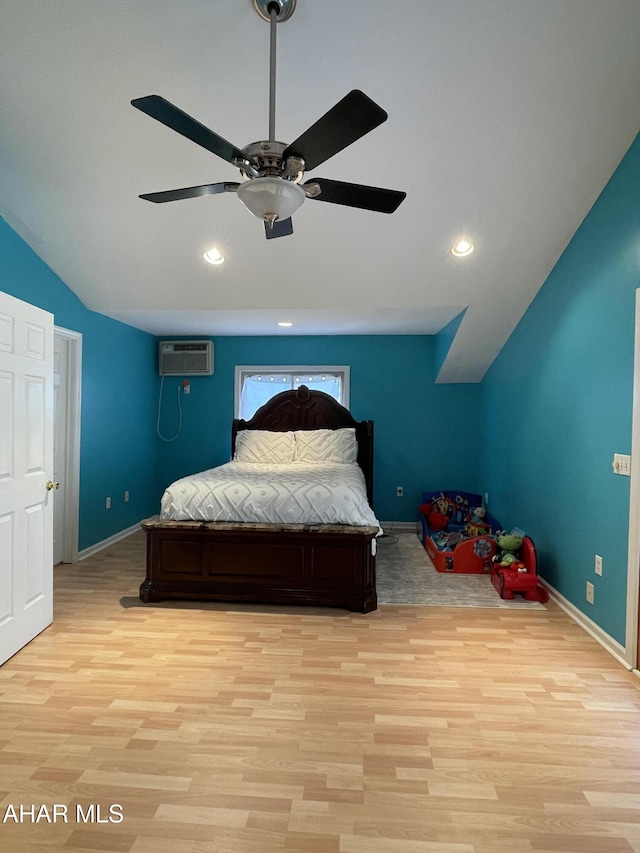 bedroom with a wall mounted AC, light wood-type flooring, vaulted ceiling, and ceiling fan