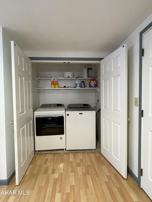 clothes washing area with separate washer and dryer and light hardwood / wood-style flooring