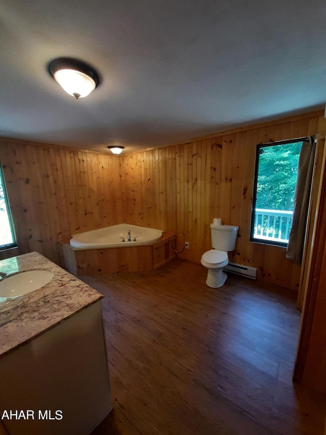 bathroom with vanity, wood walls, a bathing tub, hardwood / wood-style flooring, and toilet