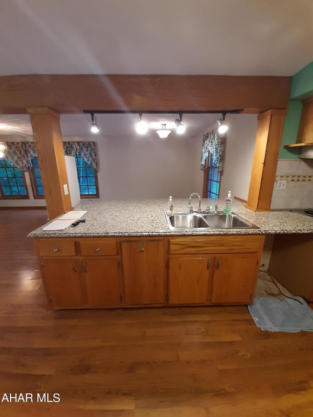 kitchen with rail lighting, kitchen peninsula, light wood-type flooring, and sink