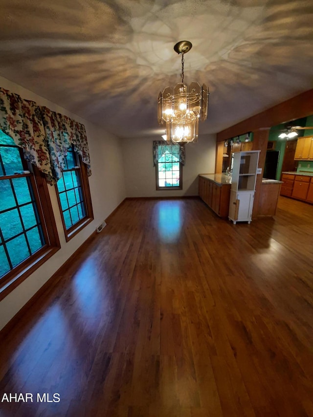 unfurnished dining area with dark hardwood / wood-style flooring and a chandelier