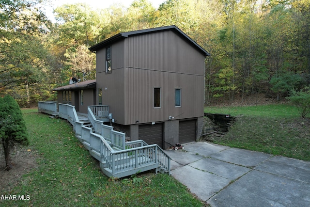 view of side of home with a wooden deck, a yard, and a garage