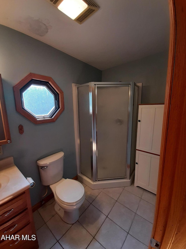 bathroom with toilet, vanity, tile patterned floors, and a shower with shower door