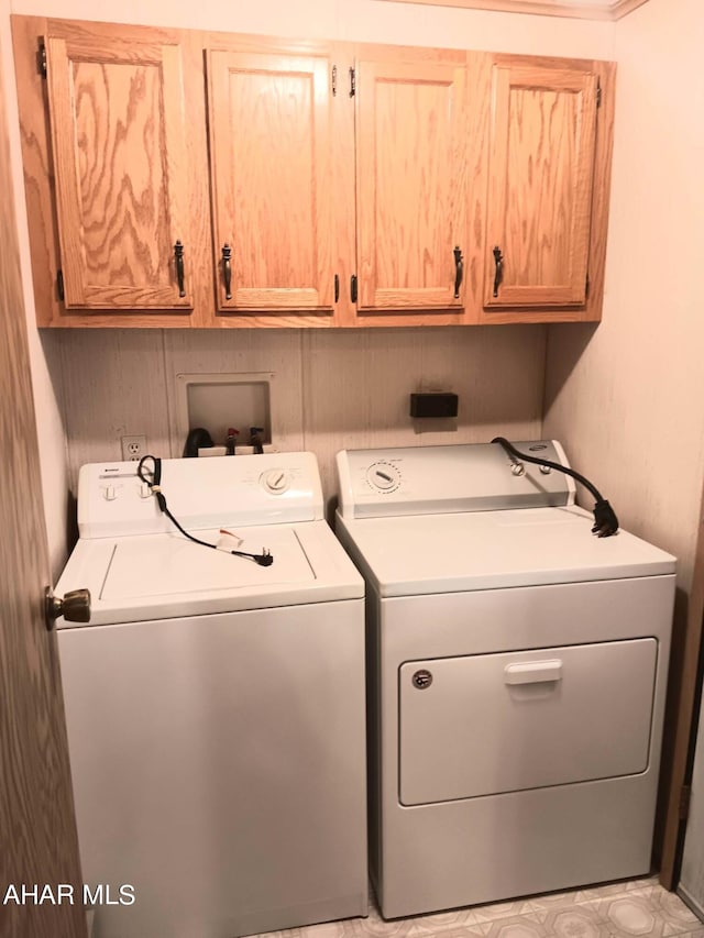 clothes washing area featuring cabinets and washing machine and clothes dryer