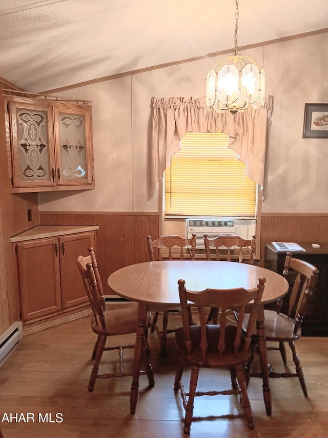 dining area featuring wood walls, an inviting chandelier, vaulted ceiling, baseboard heating, and hardwood / wood-style flooring