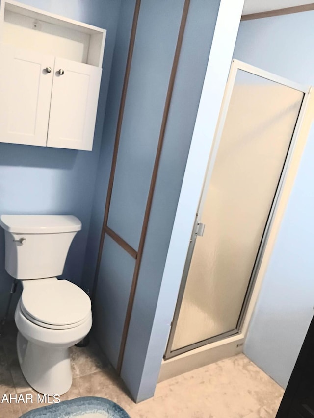 bathroom featuring a shower with shower door and toilet