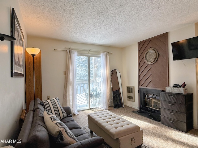 carpeted living room featuring a large fireplace and a textured ceiling