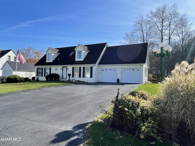 cape cod house with a front yard and a garage