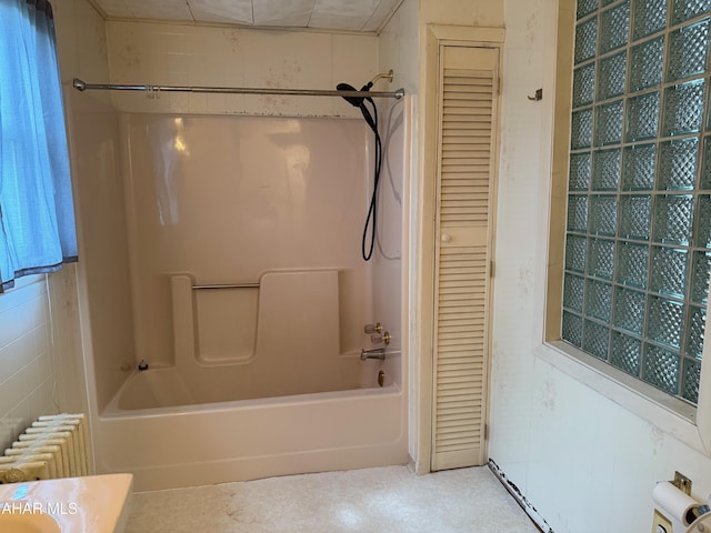 bathroom featuring radiator heating unit, a closet, and shower / washtub combination