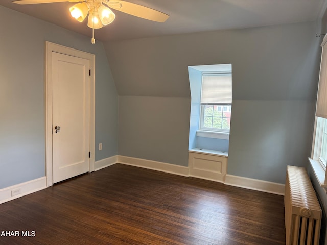 additional living space with a ceiling fan, radiator, baseboards, and dark wood-type flooring
