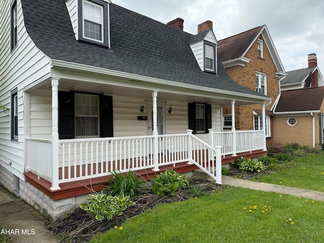 cape cod home with covered porch, roof with shingles, and a front yard