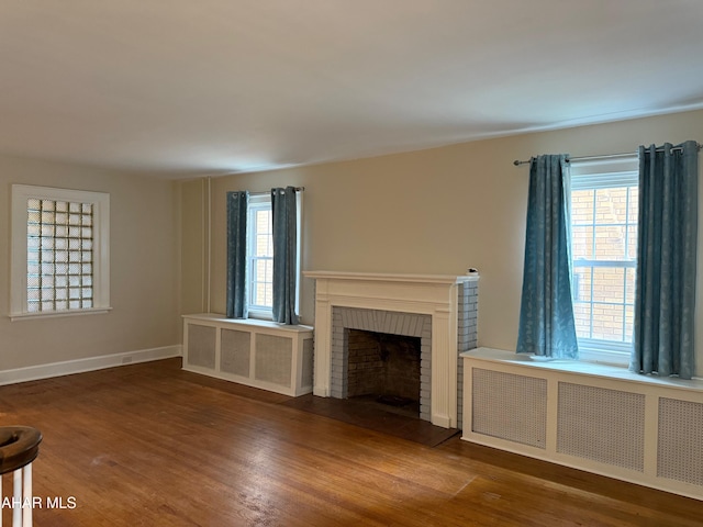 unfurnished living room with a fireplace, wood finished floors, plenty of natural light, and radiator heating unit
