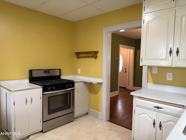 kitchen featuring gas range, light countertops, white cabinets, and light tile patterned flooring