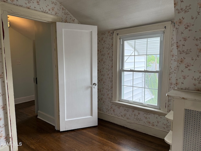 interior space with dark wood-style flooring, wallpapered walls, and multiple windows