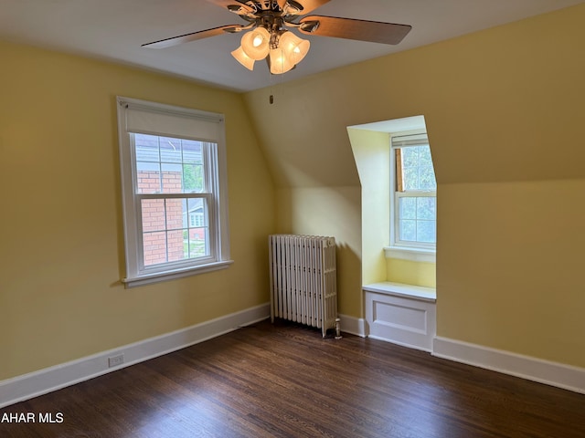 additional living space featuring lofted ceiling, baseboards, radiator heating unit, ceiling fan, and dark wood-style floors