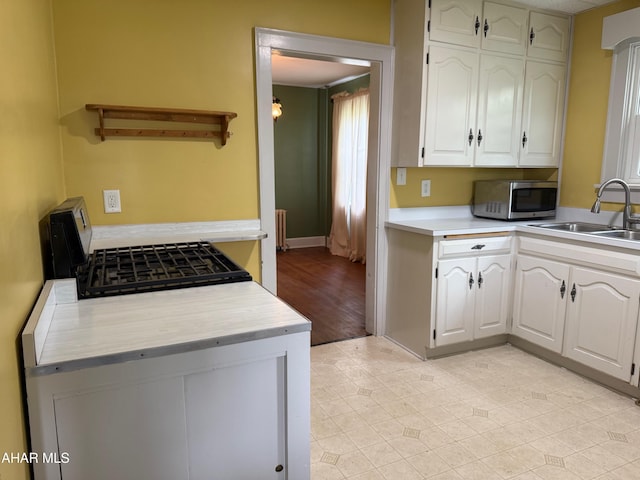 kitchen featuring light countertops, white cabinetry, stainless steel microwave, and a sink