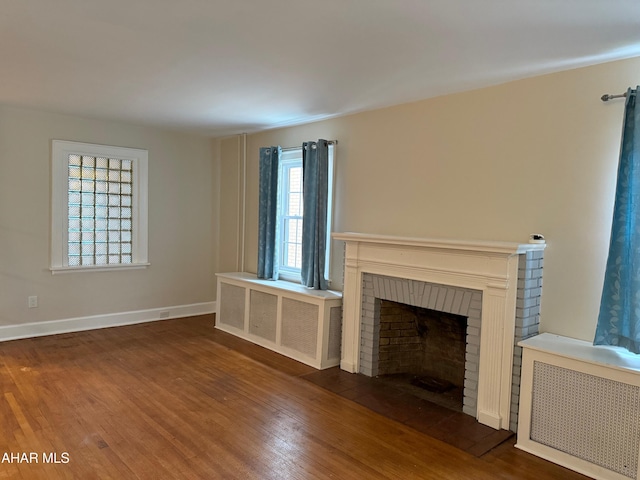 unfurnished living room featuring wood finished floors, a wealth of natural light, and radiator heating unit