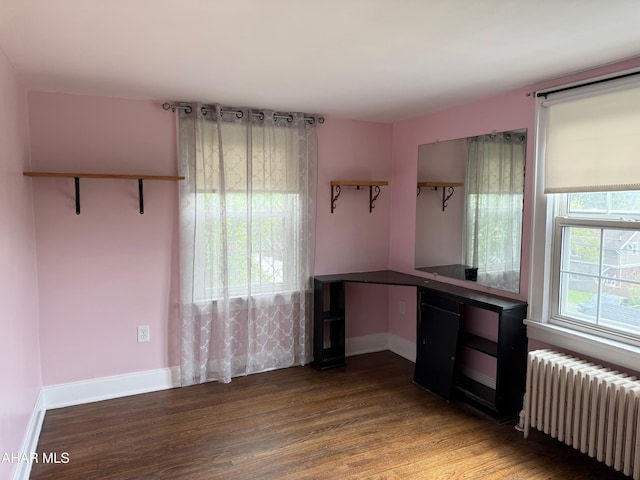 unfurnished office featuring baseboards, radiator, and wood finished floors