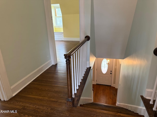 staircase featuring baseboards, a healthy amount of sunlight, and wood finished floors